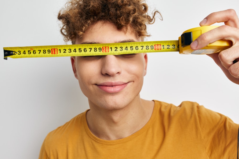 Photo of a boy holding a tape measure in front of his eyes symbolizing the correlation between brain size and substance abuse.