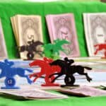 Plastic horses arranged in a race, with the piles of fake money in the background.
