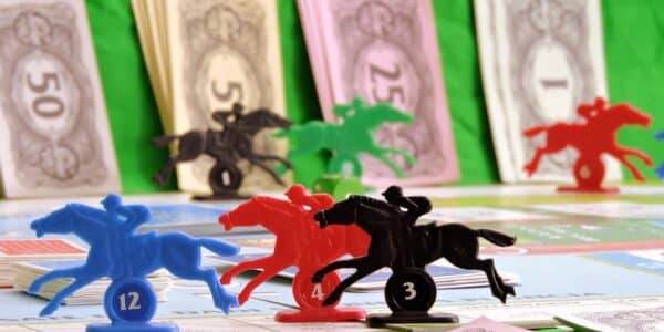 Plastic horses arranged in a race, with the piles of fake money in the background.