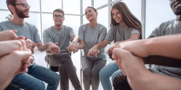 Photo of teenagers sitting in a support circle holding hands at a recovery high school.
