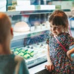 Photo of little boy and little girl looking at a display case of treats and practicing delay discounting.