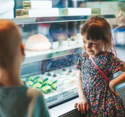 Photo of little boy and little girl looking at a display case of treats and practicing delay discounting.