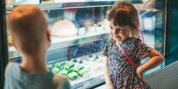 Photo of little boy and little girl looking at a display case of treats and practicing delay discounting.