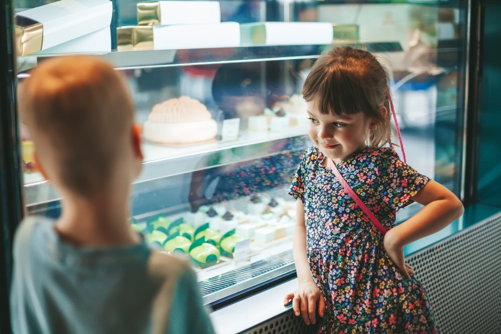 Photo of little boy and little girl looking at a display case of treats and practicing delay discounting.