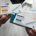 Photo of pharmacist holding two boxes of Ozempic, a GLP-1 drug being tested for use against addiction.