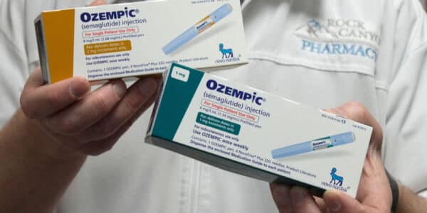 Photo of pharmacist holding two boxes of Ozempic, a GLP-1 drug being tested for use against addiction.