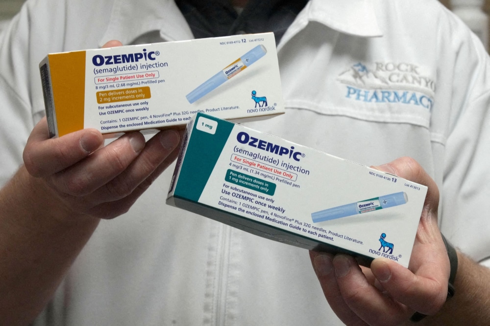 Photo of pharmacist holding two boxes of Ozempic, a GLP-1 drug being tested for use against addiction.
