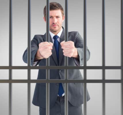 Photo of man in business suit behind bars, the result of civil commitment for people suffering substance use disorders.