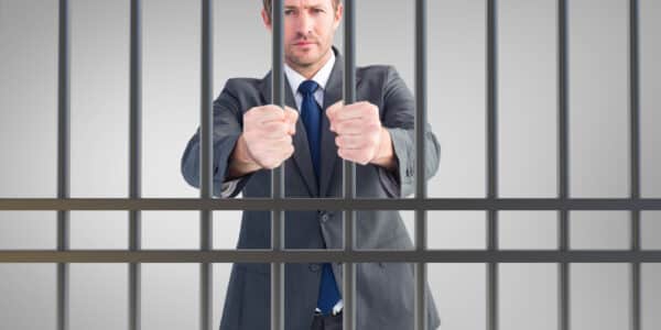 Photo of man in business suit behind bars, the result of civil commitment for people suffering substance use disorders.
