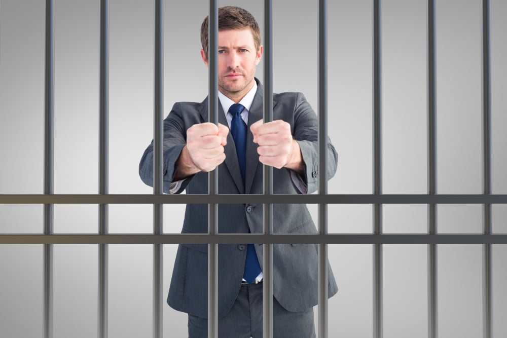 Photo of man in business suit behind bars, the result of civil commitment for people suffering substance use disorders.