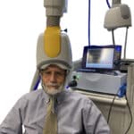 Photo of a researcher under a transcranial magnetic stimulation (TMS) cone.