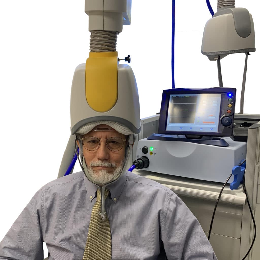 Photo of a researcher under a transcranial magnetic stimulation (TMS) cone.