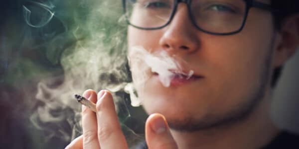 Photograph of a young man smoking a marijuana cigarette.