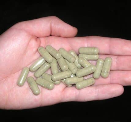 A closeup of a hand holding kratom pills.