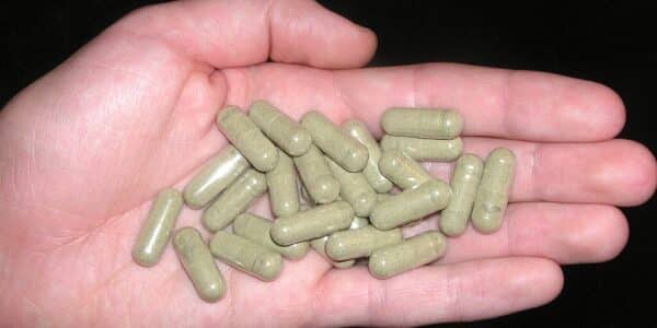 A closeup of a hand holding kratom pills.