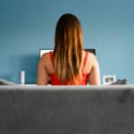 Photograph of a young woman sitting in front of a computer meant to indicate the compulsive use of pornography.