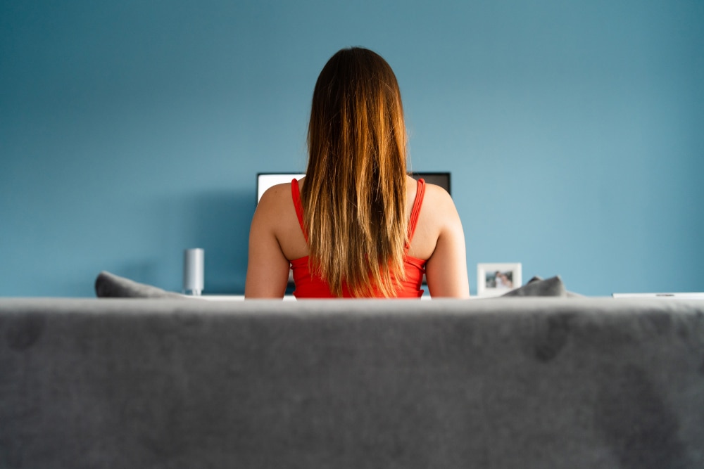 Photograph of a young woman sitting in front of a computer meant to indicate the compulsive use of pornography.