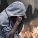 A young man in a hoodie, appearing to be in distress.