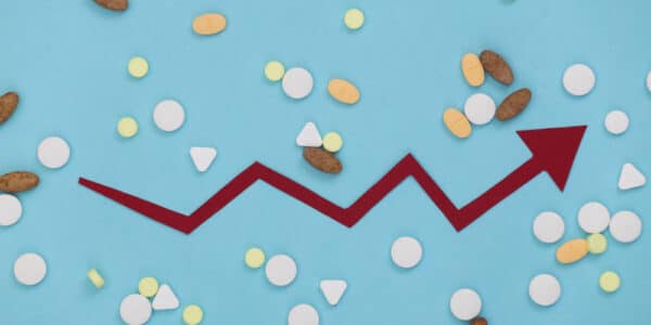 Image showing an economic growth chart amidst a background of pills symbolizing the growth of the addiction recovery economy.