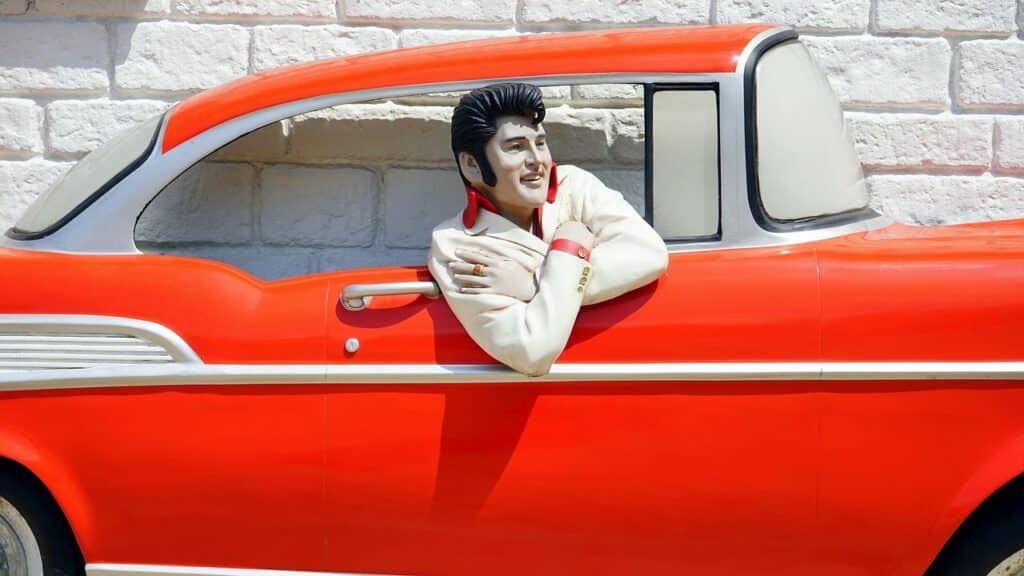 A sculpture of Elvis in a red classic car.
