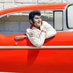 A sculpture of Elvis in a red classic car.