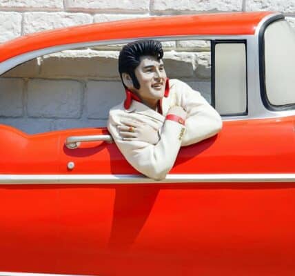 A sculpture of Elvis in a red classic car.