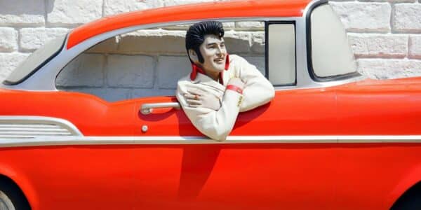 A sculpture of Elvis in a red classic car.