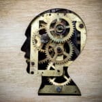 Illustration of a silhouette of the human head filled with gears, indicating the target of attentional bias modification.