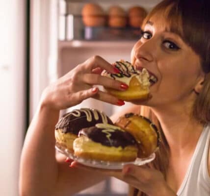Photo of a middle aged woman binge eating donuts.