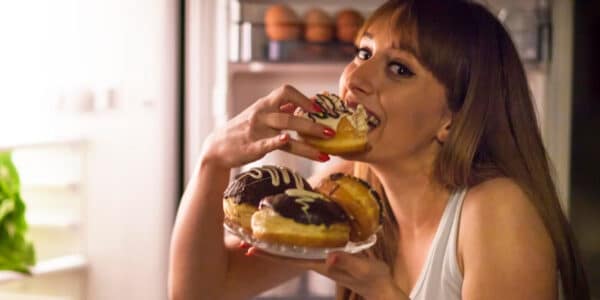 Photo of a middle aged woman binge eating donuts.