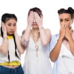 Photograph of three young, ethnically diverse women covering their ears, eyes, and mouth similar to the "hear no evil, see no evil, speak no evil" meme.
