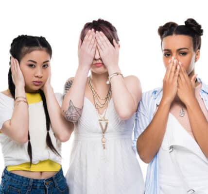 Photograph of three young, ethnically diverse women covering their ears, eyes, and mouth similar to the "hear no evil, see no evil, speak no evil" meme.