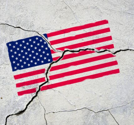 Photograph of an American flag painted onto a sidewalk that has cracked, fracturing the flag.