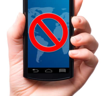 Photograph of a hand holding a smartphone and the screen displays the universal sign for "no" or "do not enter."