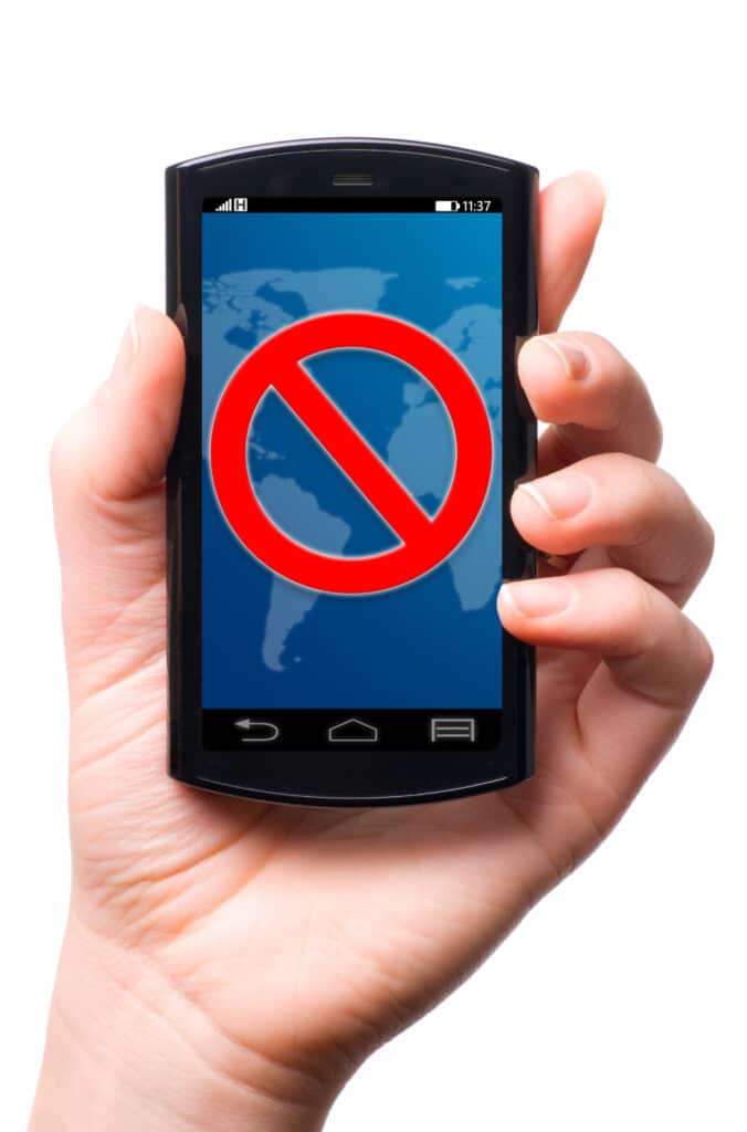 Photograph of a hand holding a smartphone and the screen displays the universal sign for "no" or "do not enter."