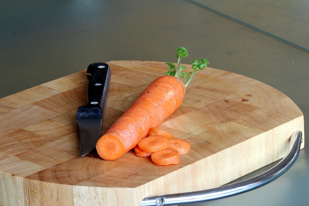 Photograph of a carrot and a knife on a cutting board.