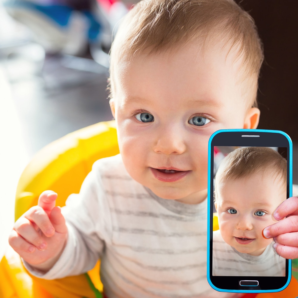 Photo of a baby taking selfie with a smartphone camera.