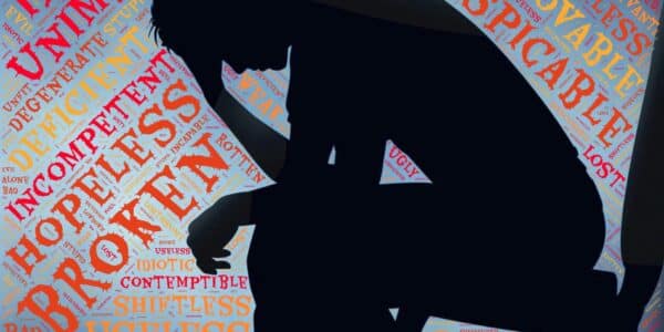 An illustration of a person having negative thoughts, represented by floating words around the person's sitting silhouette.