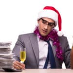 Photo of young businessman celebrating the holidays in his office with a flute of champagne.
