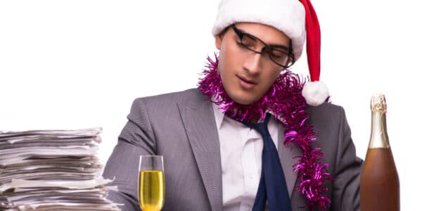 Photo of young businessman celebrating the holidays in his office with a flute of champagne.