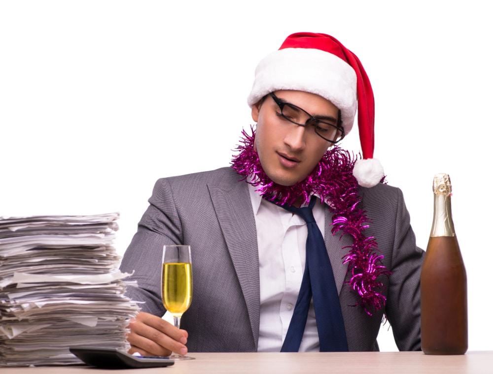 photo of young businessman celebrating the holidays in his office with a flute of champagne