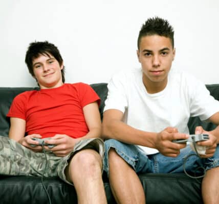 Photograph of two teenage boys holding video game controllers.