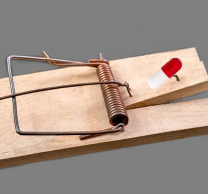 Photo of a mouse trap with a medicinal capsule on a grey background