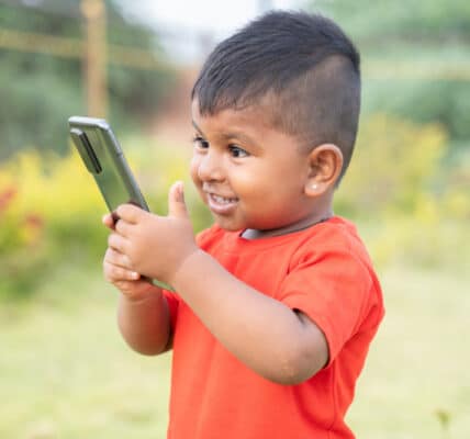 Photo of an excited child holding a smartphone.