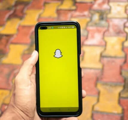 Photo of a hand holding a iPhone X with social network service Snapchat on the screen.