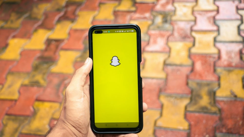 Photo of a hand holding a iPhone X with social network service Snapchat on the screen.