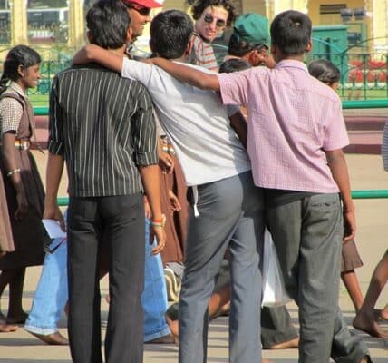 A photo three young men in a friendly embrace, with their backs turned to the viewer.