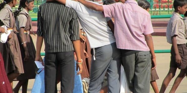 A photo three young men in a friendly embrace, with their backs turned to the viewer.