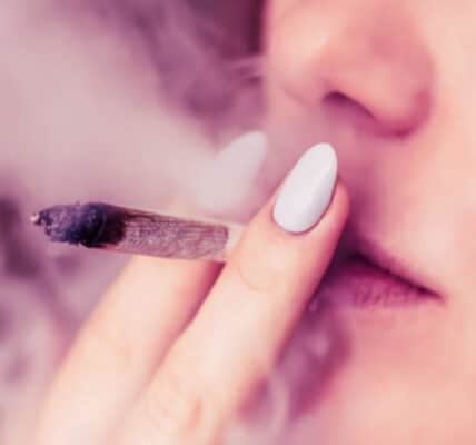 Close-up photograph of a woman smoking a marijuana cigarette.