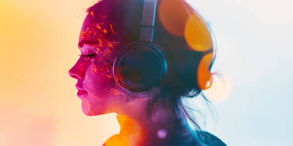 Psychedelic photograph of a woman wearing headphones and listening to music with a contemplative look on her face.